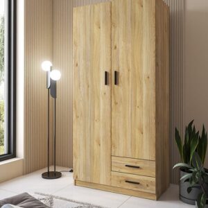 Armario de 2 puertas y 2 cajones modelo Aura en color beig con tiradores negros, instalado en un dormitorio luminoso.