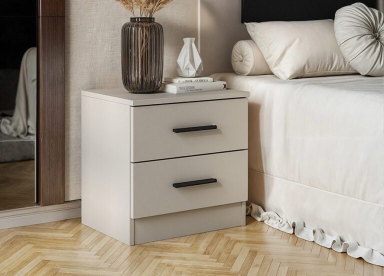 Mesita de noche Aura de estilo minimalista en color beige con dos cajones y tiradores negros, vista de frente en un dormitorio.