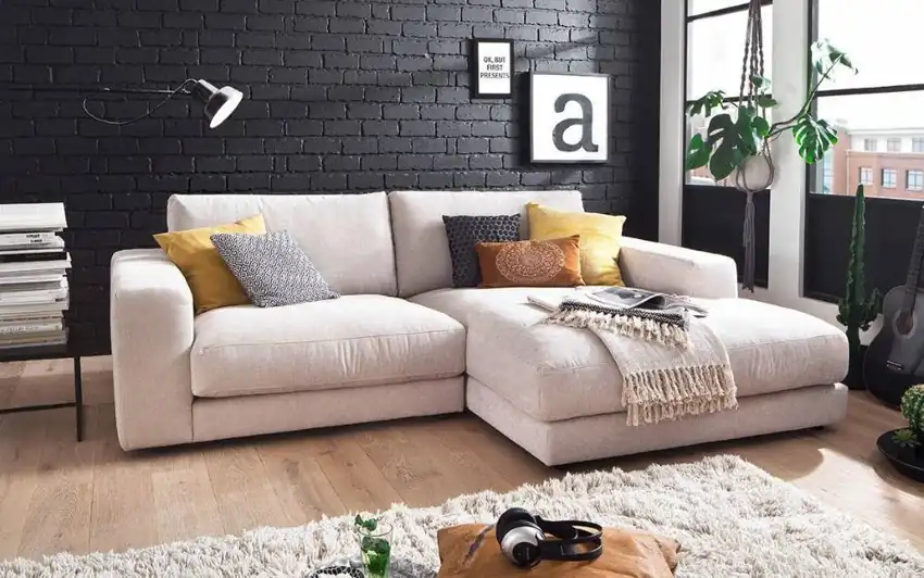 Sofá chaise longue moderno en salón luminoso con cojines decorativos, ideal para comprar sofá a plazos con Aplazame y disfrutar del máximo confort.