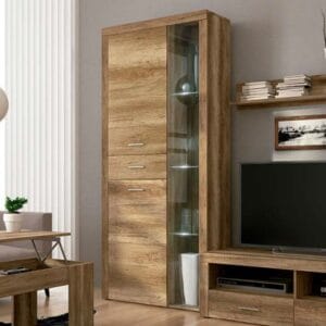 Vitrina alta con luces led Texas en color cañón, con el lateral de cristal y las luces encendidas, exhibiendo decoración en un salón moderno.