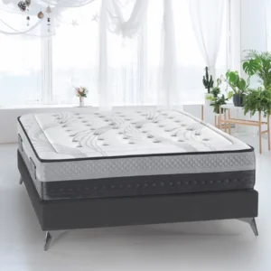 Colchón híbrido Remo de firmeza media sobre un somier en un dormitorio luminoso, destacando su tejido acolchado y grosor.