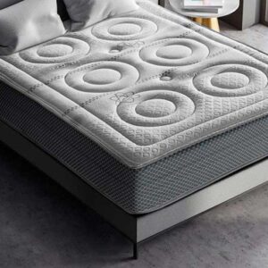 Colchón Cool Fresh de muelles ensacados sobre una base tapizada en un dormitorio moderno y luminoso, destacando su tejido superior.