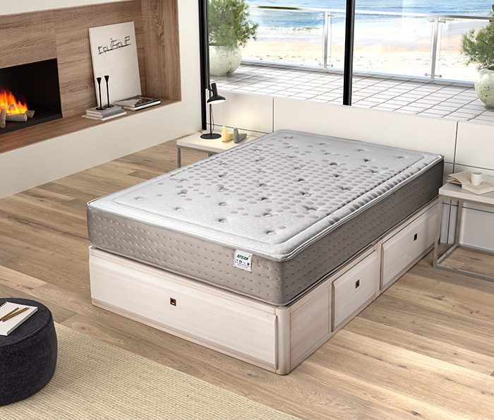 Colchón Golden de muelles ensacados y viscoelástica sobre un canapé en un dormitorio luminoso, mostrando su grosor y tejido suave.