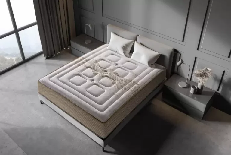 Colchón viscoelástico Premium sobre una base de cama en un dormitorio luminoso, mostrando su tejido acolchado y grosor.