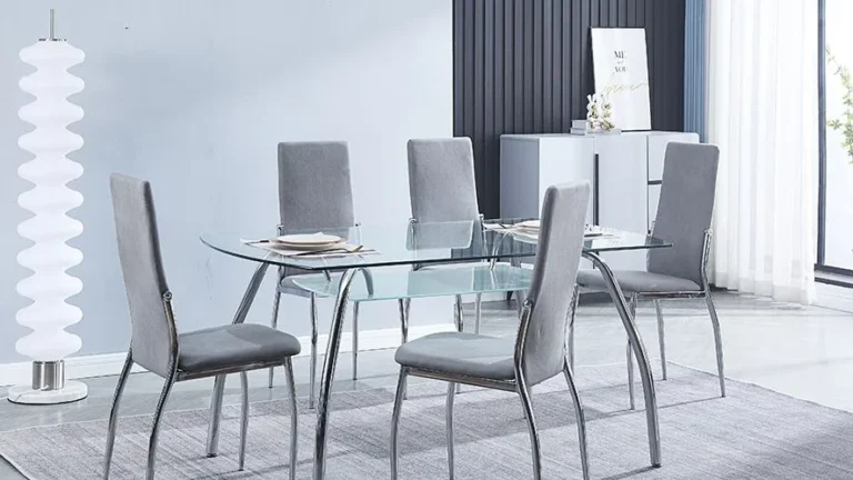 Conjunto de comedor moderno con la mesa San de cristal templado y patas cromadas junto a seis sillas Sakura tapizadas en tela color marengo en un salón luminoso.