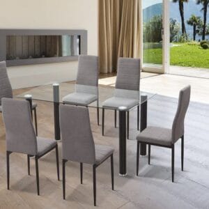 Conjunto de comedor Yuri con mesa rectangular de cristal transparente y patas de acero negro junto a seis sillas tapizadas en microfibra gris marengo en un comedor moderno y luminoso.