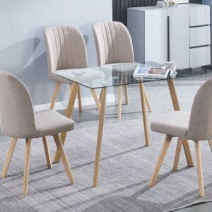 Conjunto de mesa Acnes de cristal templado rectangular y 4 sillas Lane tapizadas en tela beige y gris con patas de pino, en un comedor moderno y luminoso.