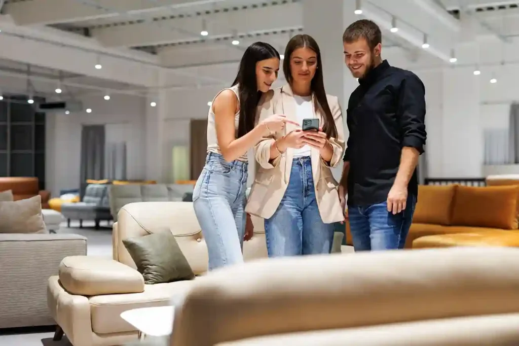3 personas comparando tiendas de muebles online desde una exhibición de muebles