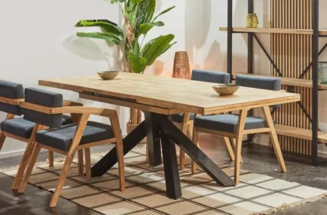 Mesas de comedor para 10 personas con superficie de madera maciza y base de forja en salón con tonos naturales
