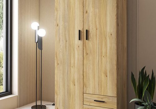 Armario de 2 puertas y 2 cajones modelo Aura en color beig con tiradores negros, instalado en un dormitorio luminoso.