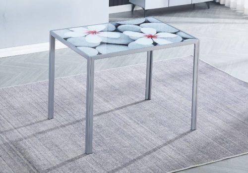 Mesa de cocina moderna Flores con tapa de cristal estampada de flores y patas metálicas grises, en una cocina compacta y luminosa ideal para desayunos y comidas rápidas.