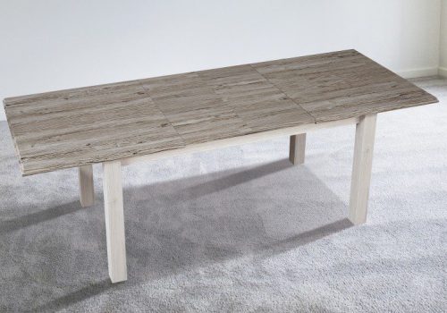 Mesa de comedor extensible Irma con tablero de madera técnica en acabado gris y base blanca bicolor, lista para 6-8 personas en un ambiente familiar moderno y luminoso, acompañada de sillas acogedoras y vajilla preparada para una cena especial.
