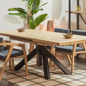 Mesa de comedor extensible de madera maciza para 8 a 10 personas, con patas de forja, desplegada en un comedor familiar, rodeada de invitados disfrutando de una cena animada.