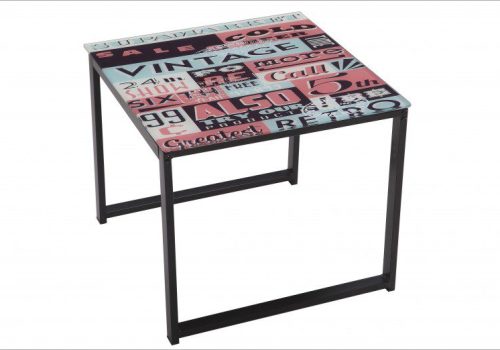 Mesita de centro cuadrada Danubio de cristal con patas de metal, situada junto a un sofá en un salón con decoración moderna y libros encima.