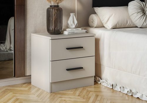 Mesita de noche Aura de estilo minimalista en color beige con dos cajones y tiradores negros, vista de frente en un dormitorio.